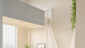 A modern room with a desk, shelving, a ladder, and a potted plant. - Middle of DOWNTOWN VANCOUVER INDEPENDENT APARTMENT SLEEPS 4 (Vancouver)