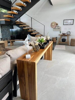 Ein modernes Wohnzimmer mit Couch, Fernseher und einer Wendeltreppe sowie einem Holztisch.