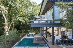Ein modernes Haus mit Pool, Sitzgelegenheit im Freien und Essbereich.