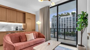 Ein modernes Wohnzimmer mit einem rosa Sofa, einem Holztisch und einem großen Fenster mit Blick auf die Stadt.