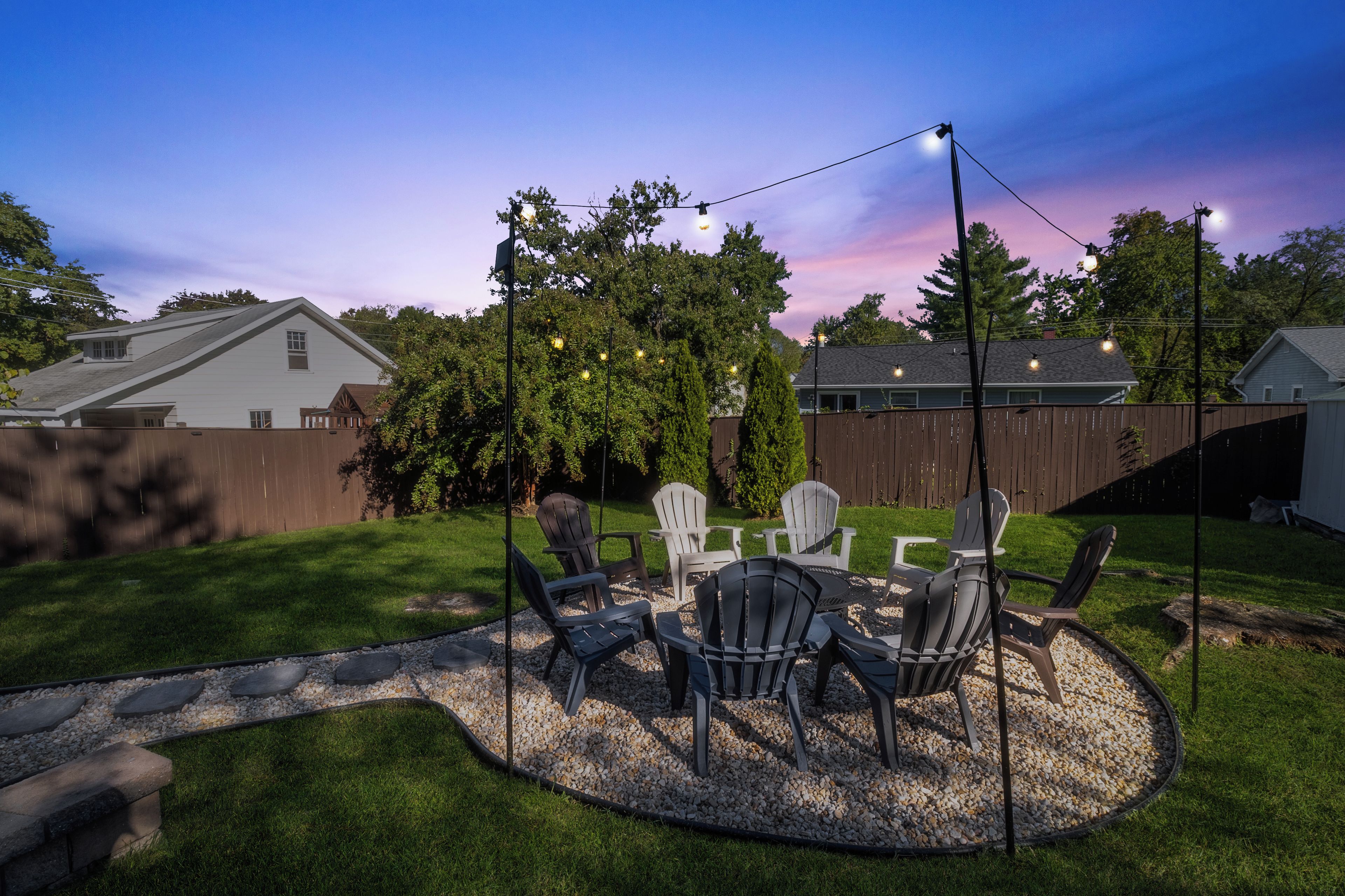A backyard patio with a round table and chairs, surrounded by a gravel area.