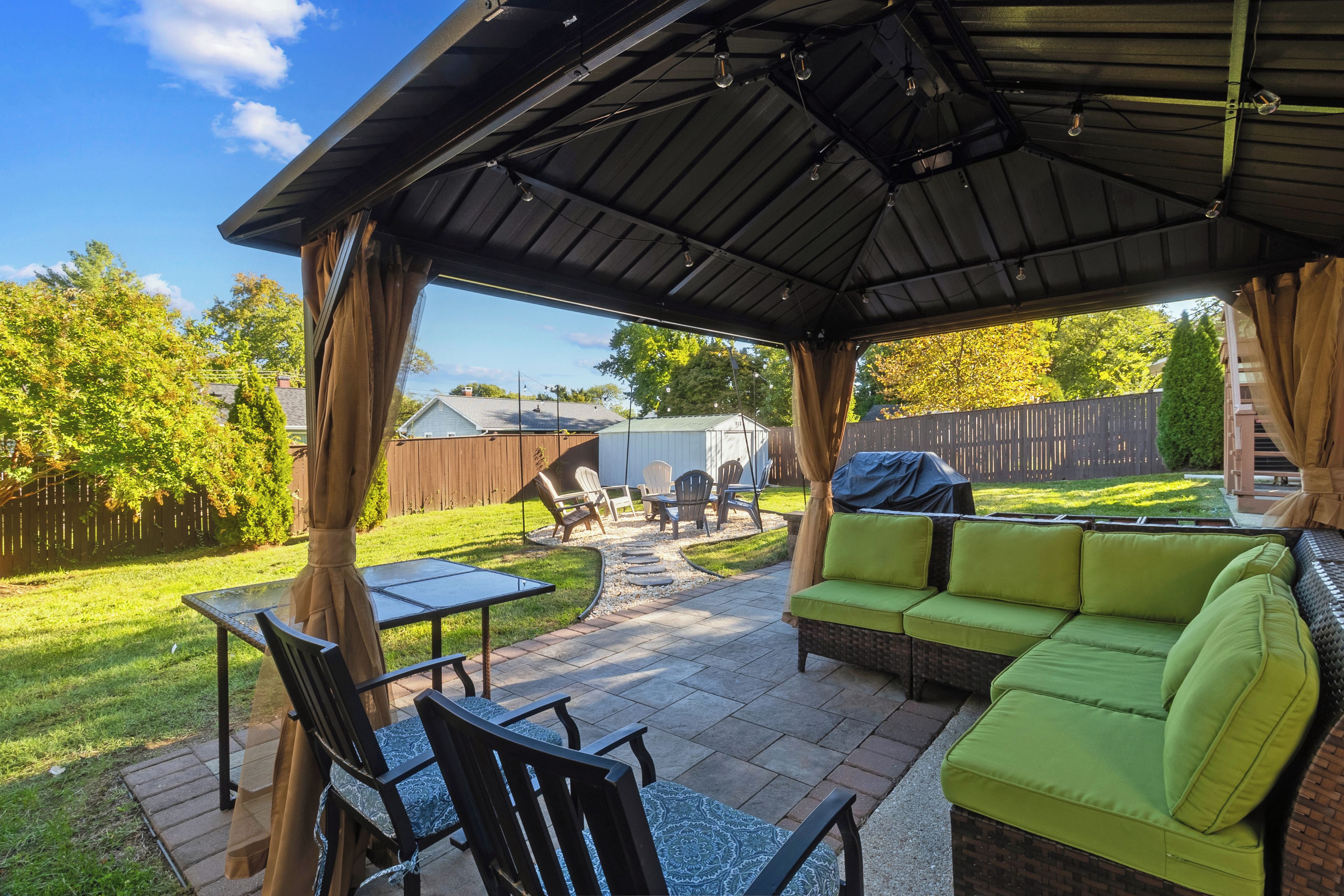 A covered patio area with a green sofa, a dining table, and chairs.