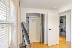 Ein Zimmer mit Holzboden, einer weißen Tür und Blick auf einen Balkon mit Rollläden.