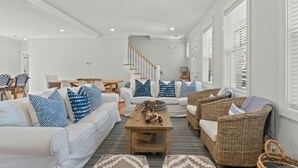 Ein geräumiges Wohnzimmer mit einem weißen Sofa, Korbstühlen und einem Holztisch.