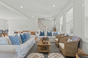 Ein geräumiges Wohnzimmer mit einem weißen Sofa, Korbstühlen und einem Holztisch.