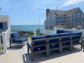 Eine Terrasse mit einer Couch und Sesseln mit Blick auf den Ozean.