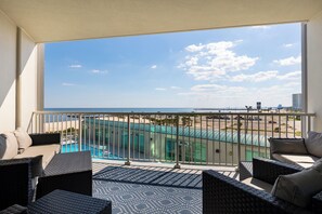 Ein Balkon mit Korbmöbeln, Blick auf den Strand und ein Pool.