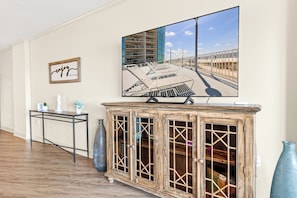 Ein Wohnzimmer mit Fernseher, Schrank und gerahmtem Zitat an der Wand.