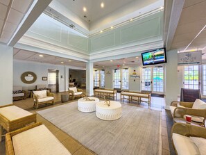 Eine geräumige Lobby mit Korbmöbeln, einem großen Fernsehbildschirm und einem Schild für 'Cenote Day Spa'.