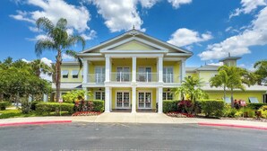 A two-story hotel with a central entrance, a balcony on the second floor, and a tower on the roof. - Family 808 Cozy Poolside Retreat  2BR 2BA (Davenport)