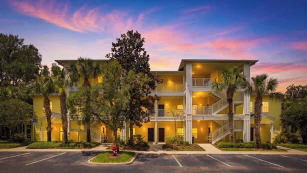 A multi-story hotel with a central courtyard, balconies, and a parking lot. - Family 808 Cozy Poolside Retreat  2BR 2BA (Davenport)