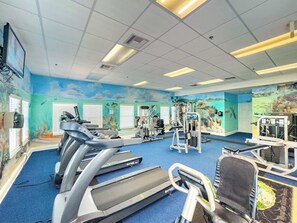 Ein Fitnessstudio mit Laufbändern, Kraftgeräten und Wandmalereien.
