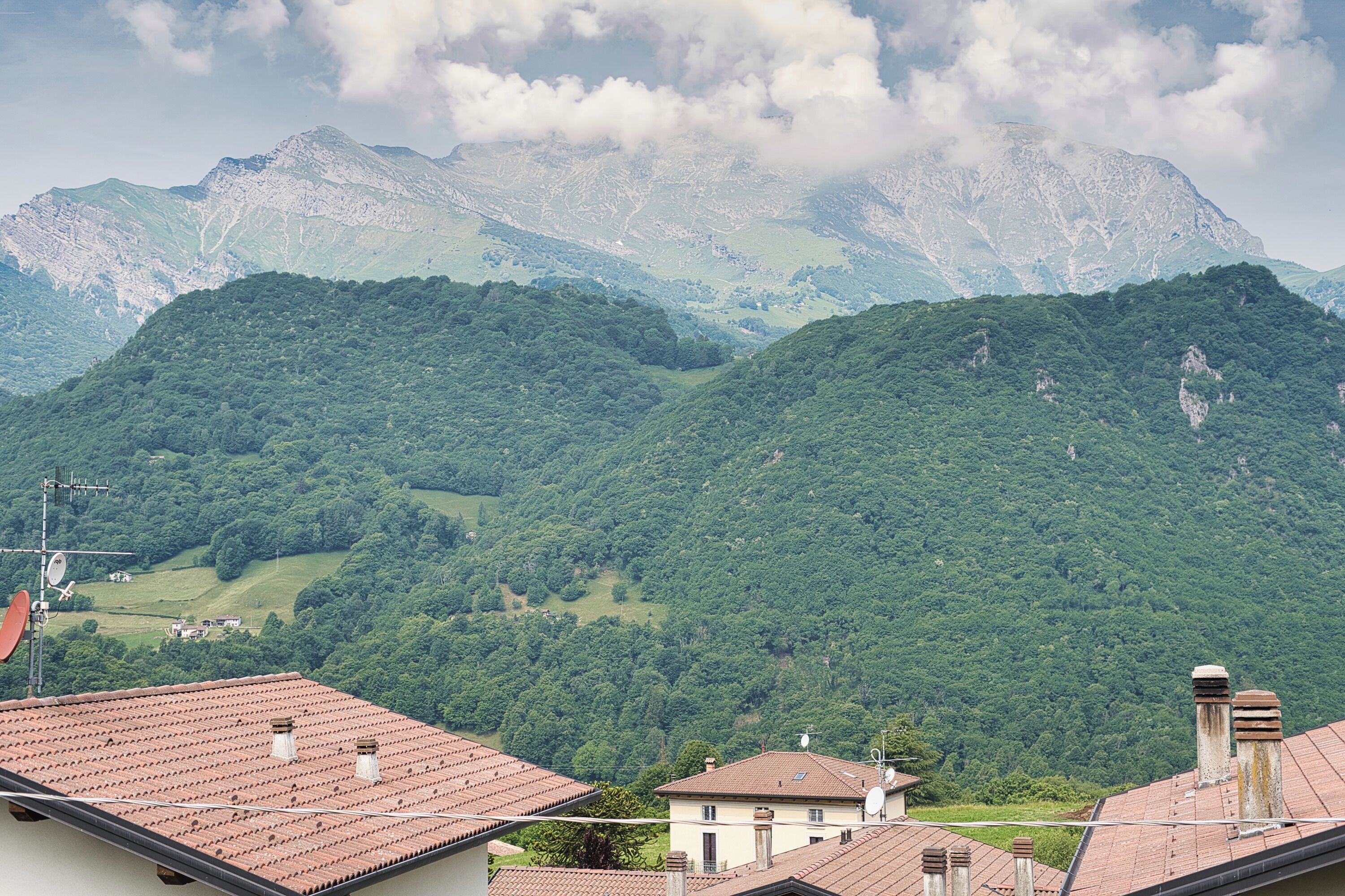 A mountainous landscape with residential buildings featuring red-tiled roofs and satellite dishes.