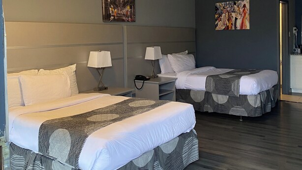 Ein Hotelzimmer mit zwei Betten, einem Nachttisch, einer Lampe, einem Gemälde und einer Deckenleuchte.