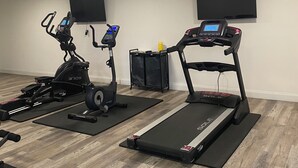 A home gym with two treadmills, a stationary bike, and a weight bench. - Affordable King Room Stay (New Orleans)