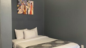 A bedroom with a bed, a painting on the wall, and a ceiling light. - Affordable King Room Stay (New Orleans)