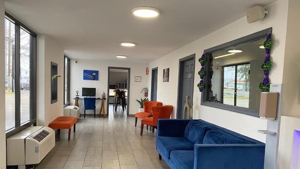 A reception area with a blue sofa, orange chairs, a TV, and a window with a view. - Affordable King Room Stay (New Orleans)