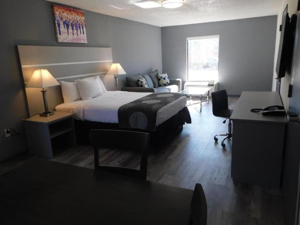 Une chambre d’hôtel moderne équipée d’un lit, d’un bureau, d’une chaise et d’une fenêtre.