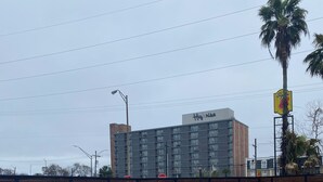 A swimming pool with a wooden fence, a stop sign, and a building labeled 'Highrise' in the background. - Affordable King Room Stay (New Orleans)