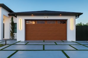 Ein modernes Haus mit einer Garage, Hausnummer 618, einer Holztür und einer gepflegten Auffahrt.