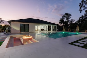 Ein modernes Haus mit Swimmingpool, Feuerstelle und einer Terrassenfläche.