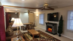 Un salon doté d’une cheminée, d’un ventilateur de plafond, d’un téléviseur et d’un coin repas.