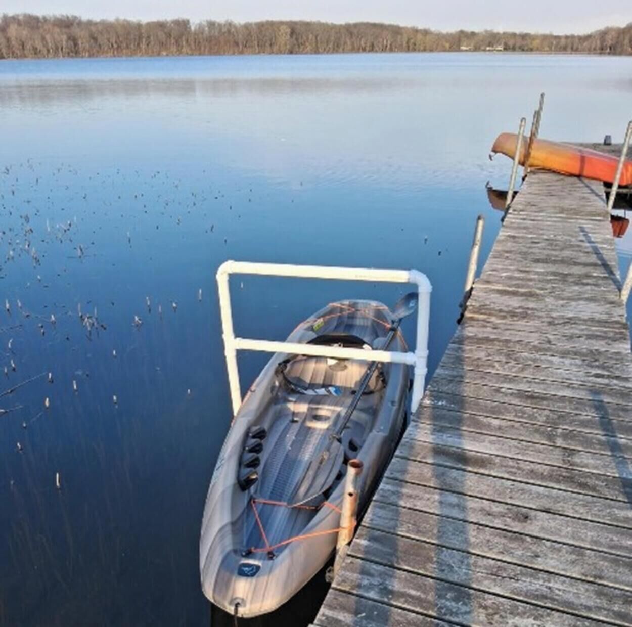 A kayak docked at a wooden pier extending into a calm body of water.