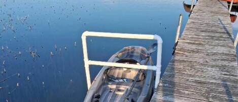 A kayak docked at a wooden pier extending into a calm body of water.