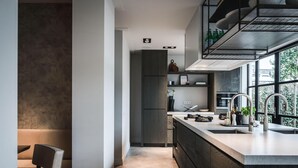 Een moderne keuken met een centraal eiland, ingebouwde apparatuur en een raam dat natuurlijk licht binnenlaat.