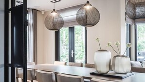 Een moderne eetruimte met een lange tafel, meerdere stoelen en decoratieve vazen.