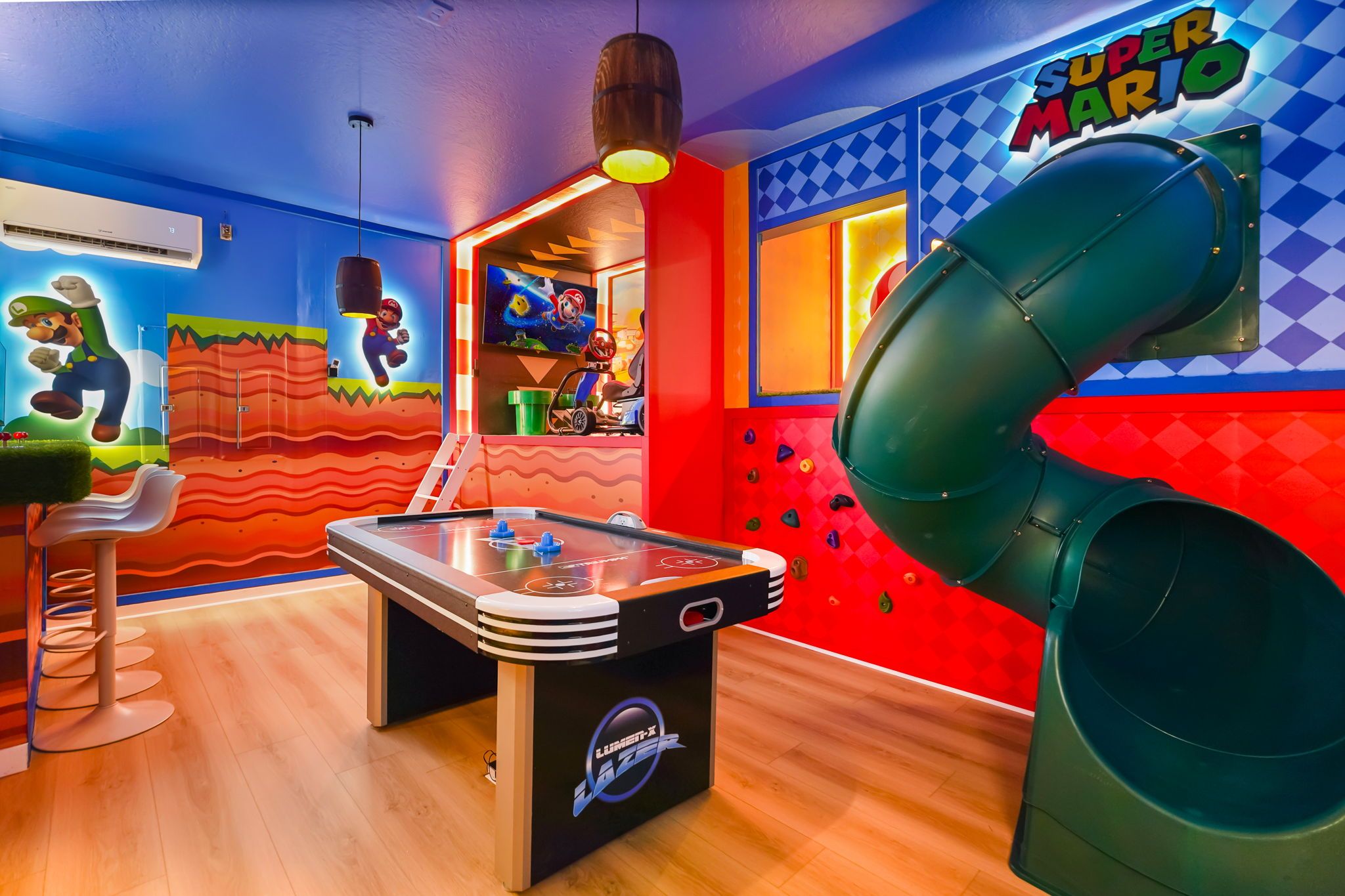 A room with a foosball table, a slide, and colorful Mario-themed decorations.