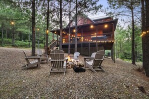 Eine Hütte mit Feuerstelle, Sitzgelegenheiten im Freien und Lichterketten.