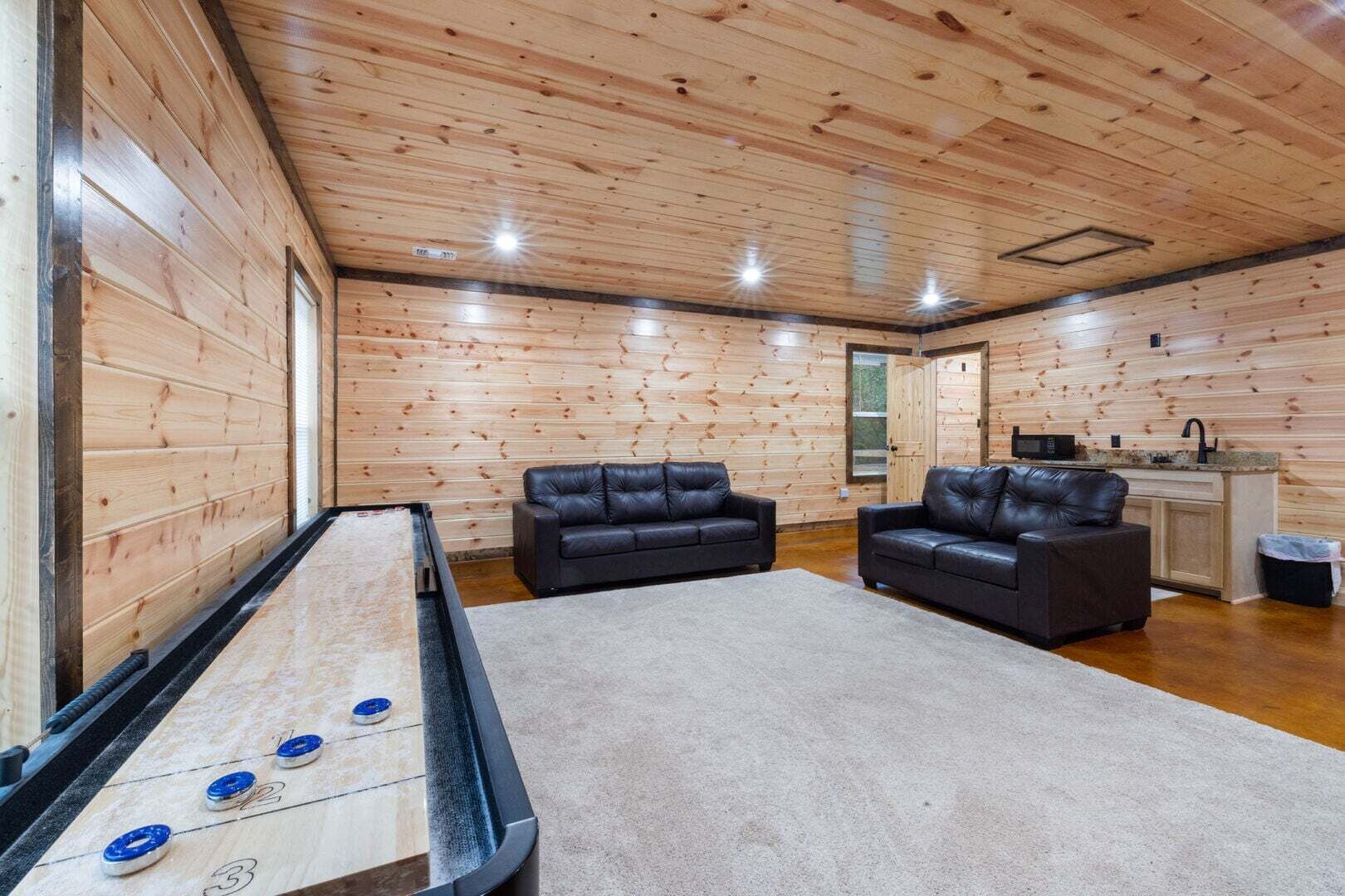 Een gezellige kamer met een tafel voor jeu de boules, twee leren banken en een kitchenette.