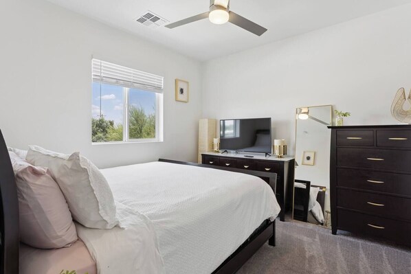 A bedroom with a bed, a TV, a dresser, and a ceiling fan. - PHX Home Spa Fire Pit Outdoor Projector (Phoenix)