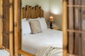 A neatly made bed with a patterned bedspread, a headboard with vertical wooden slats, and a bedside lamp. - Tropical Backyard Oasis in Cocoa Beach | Heated Pool, BBQ Grill & Fire Pit ☀️ (Cocoa Beach)