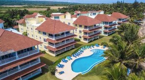 Ein Resort mit mehreren Gebäuden, einem Schwimmbad und einem Strand.