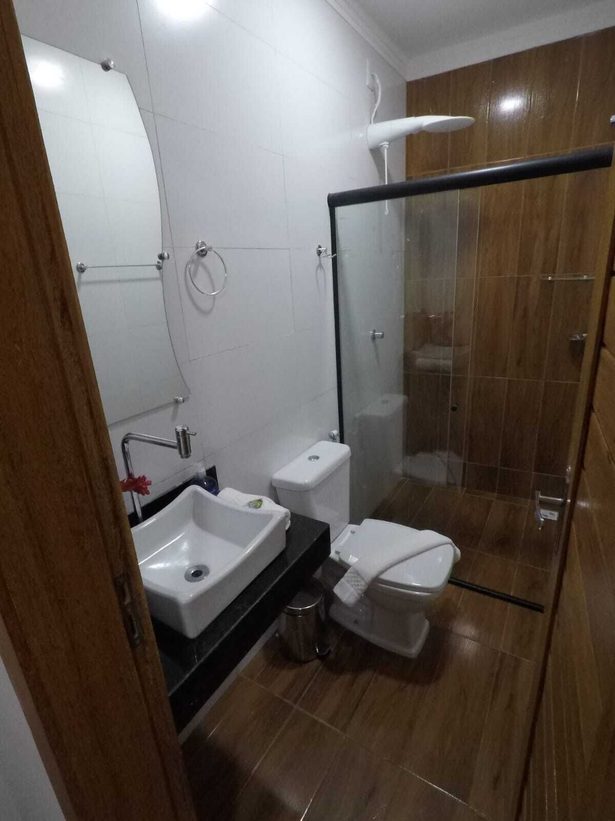 A modern bathroom with a glass shower enclosure, a white sink, and a toilet.