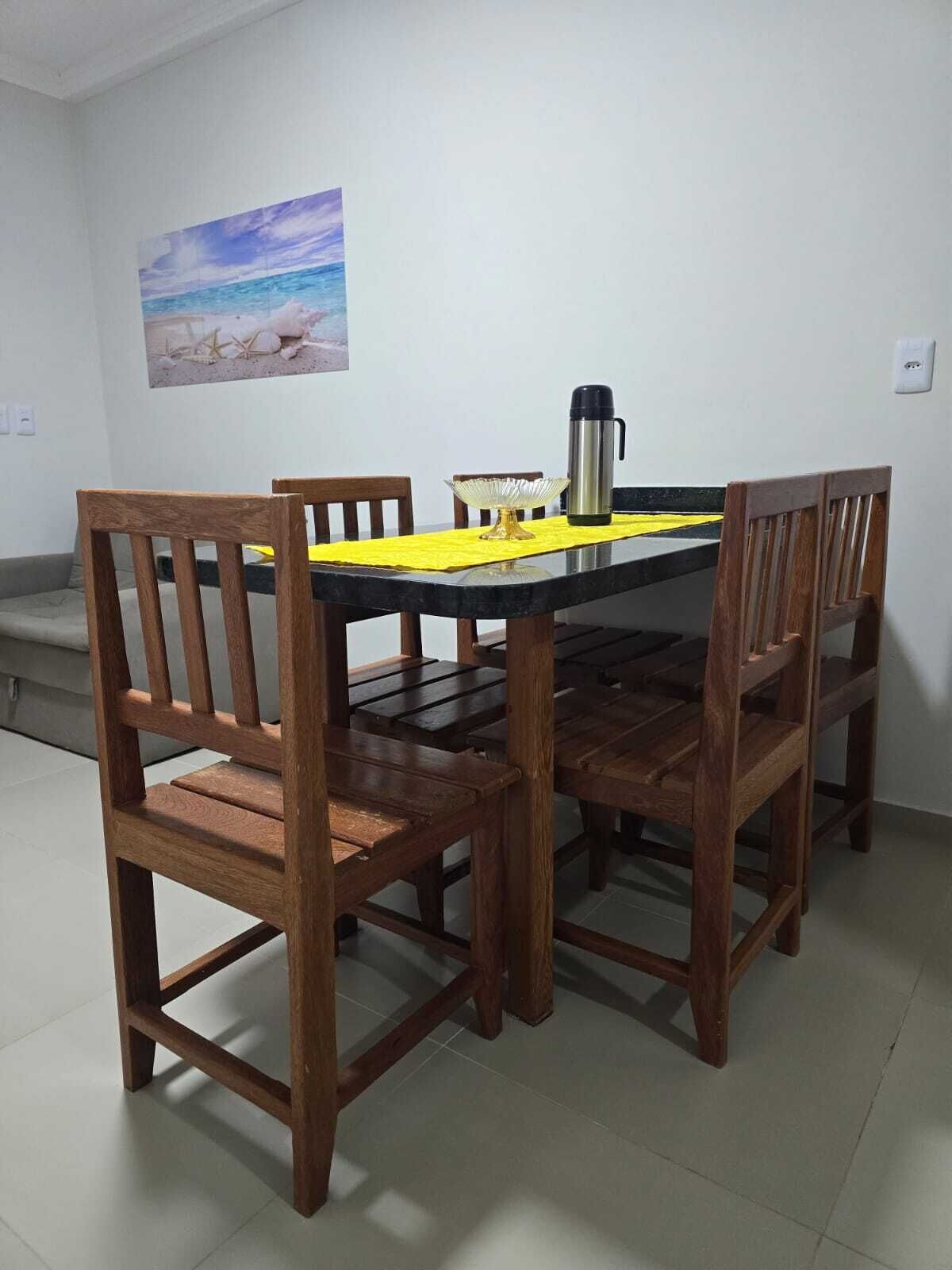 A dining table with chairs, a yellow placemat, and a black thermos.