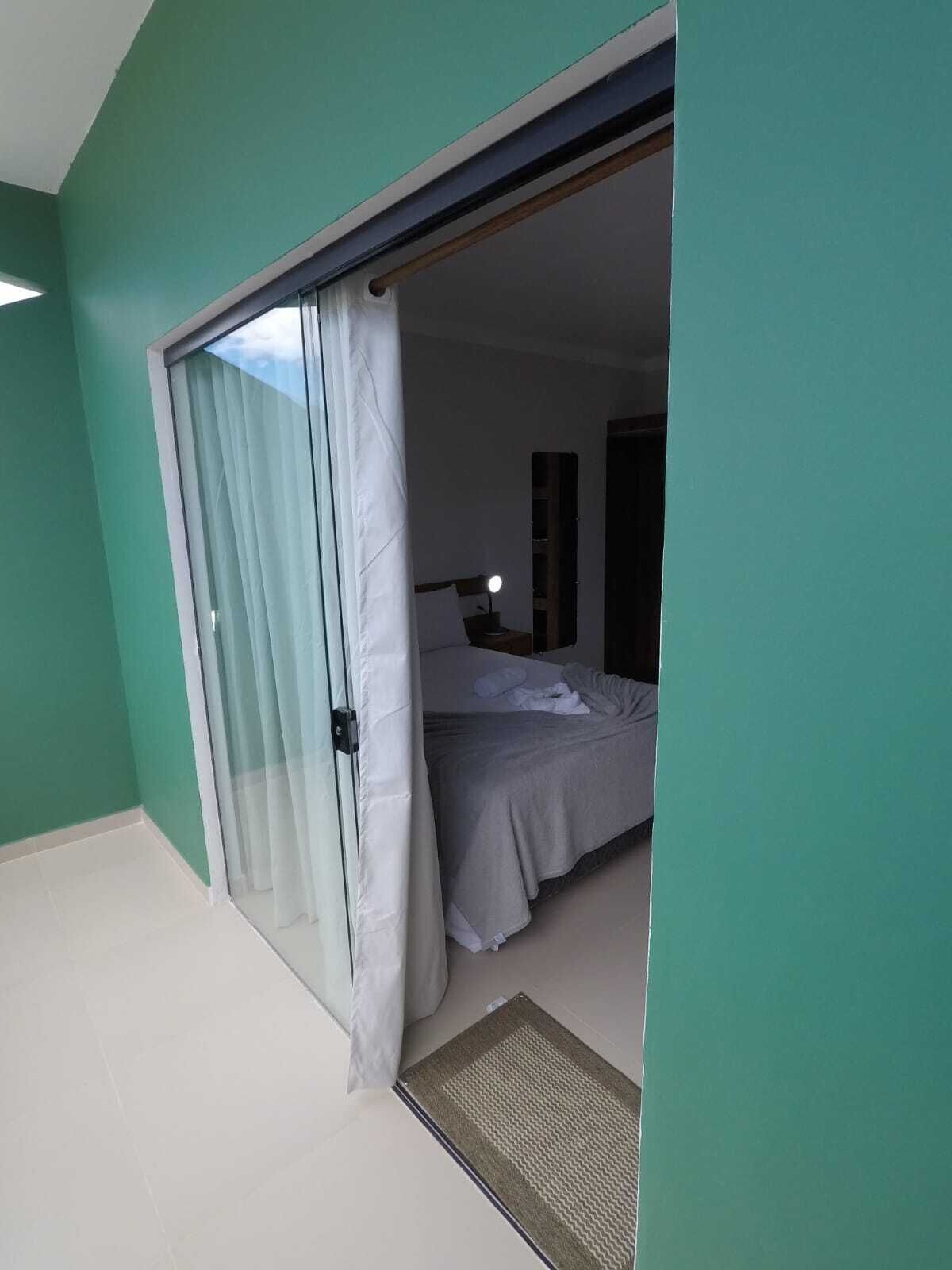 A room with a bed, a desk with a lamp, and a sliding door leading to another room.