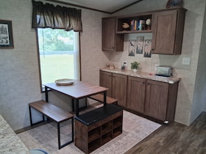 A compact kitchen with a dining table, bench, and built-in cabinets.