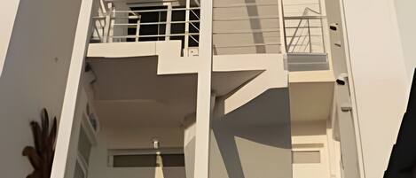 Un edificio de varios pisos con una escalera central, balcones y un diseño arquitectónico moderno.