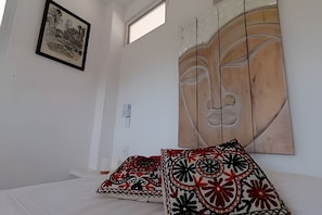A room with a bed, a large wall painting, and a framed picture.