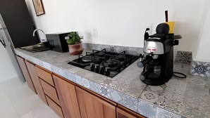 Ett kök med en gasspis, en kaffebryggare och en krukväxt.
