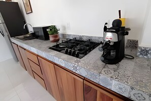Una cocina con estufa a gas, cafetera y una planta en maceta.