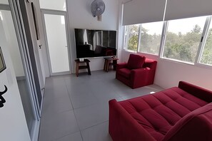 Una sala de estar moderna con un televisor de pantalla plana grande, sofás rojos y una mesita pequeña.