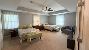 Ein Schlafzimmer mit zwei Betten, einem Deckenventilator, einem Schreibtisch und einem Stuhl.