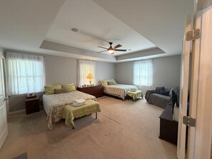 Ein Schlafzimmer mit zwei Betten, einem Deckenventilator, einem Schreibtisch und einem Stuhl.