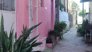 A narrow alleyway with a pink building, potted plants, and a visible number '404' on the wall.