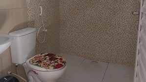 A bathroom with a toilet, bidet, and shower area.