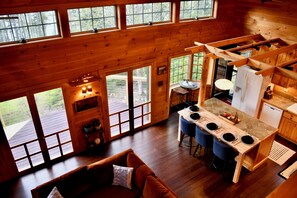 Eine Hütte mit Essbereich, Küche und einem großen Fenster mit Blick auf eine Terrasse.